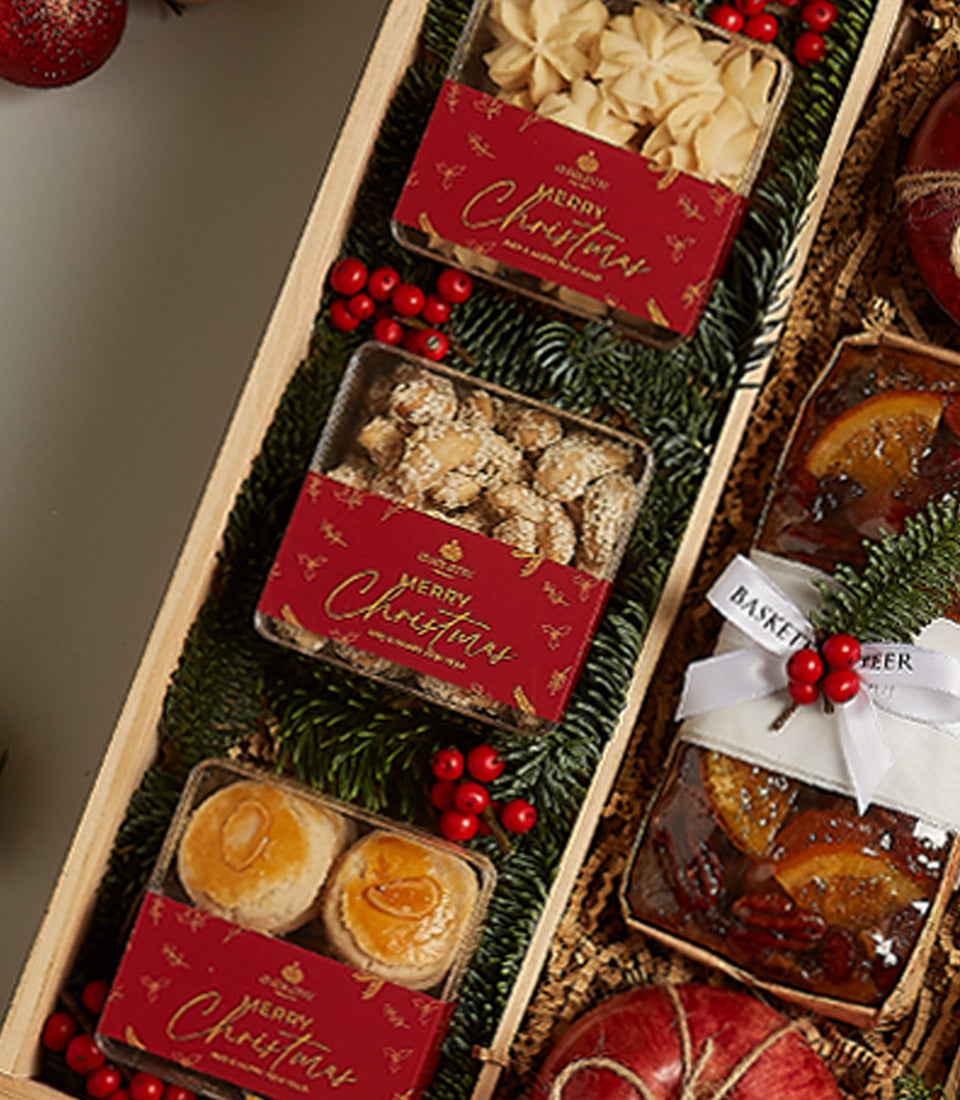 Luxury Christmas hamper with star cookies, festive baked goods, and fruitcake in wooden box lined with pine and berries
