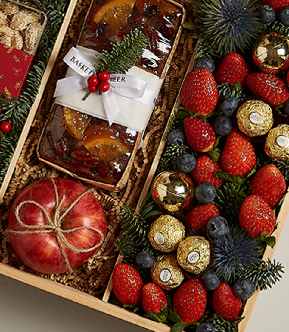 Festive luxury hamper with gourmet fruitcake, fresh berries, gold truffles, and festive ornaments in natural wood