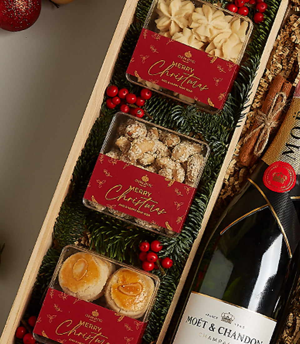 Luxury champagne hamper with star cookies, glazed nuts, and almond pastries in festive wooden tray for Christmas