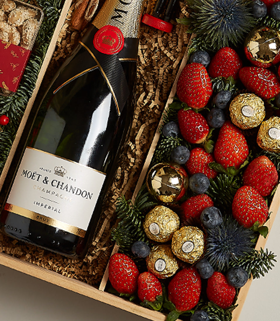 Luxury champagne and festive fruit hamper with Moët & Chandon, strawberries, blueberries, and gold chocolates in wooden gift