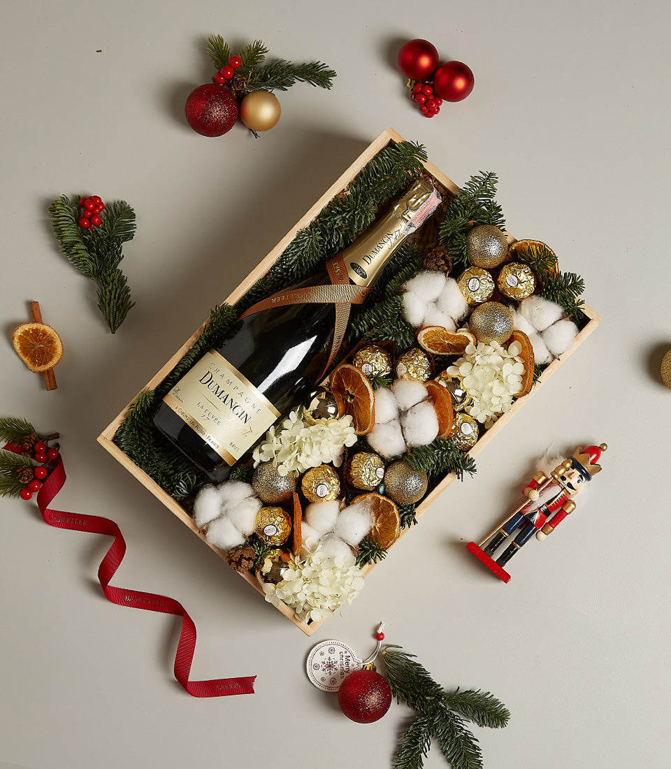 Luxury champagne and Ferrero Rocher gift box with gold baubles, dried citrus, and festive greenery for Christmas