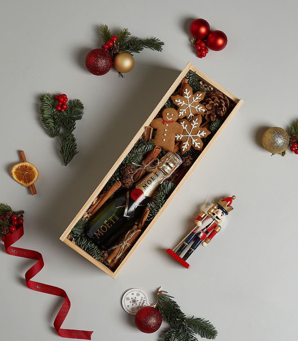 Golden Moët champagne Christmas gift box with gingerbread cookies, pine, and festive ornaments