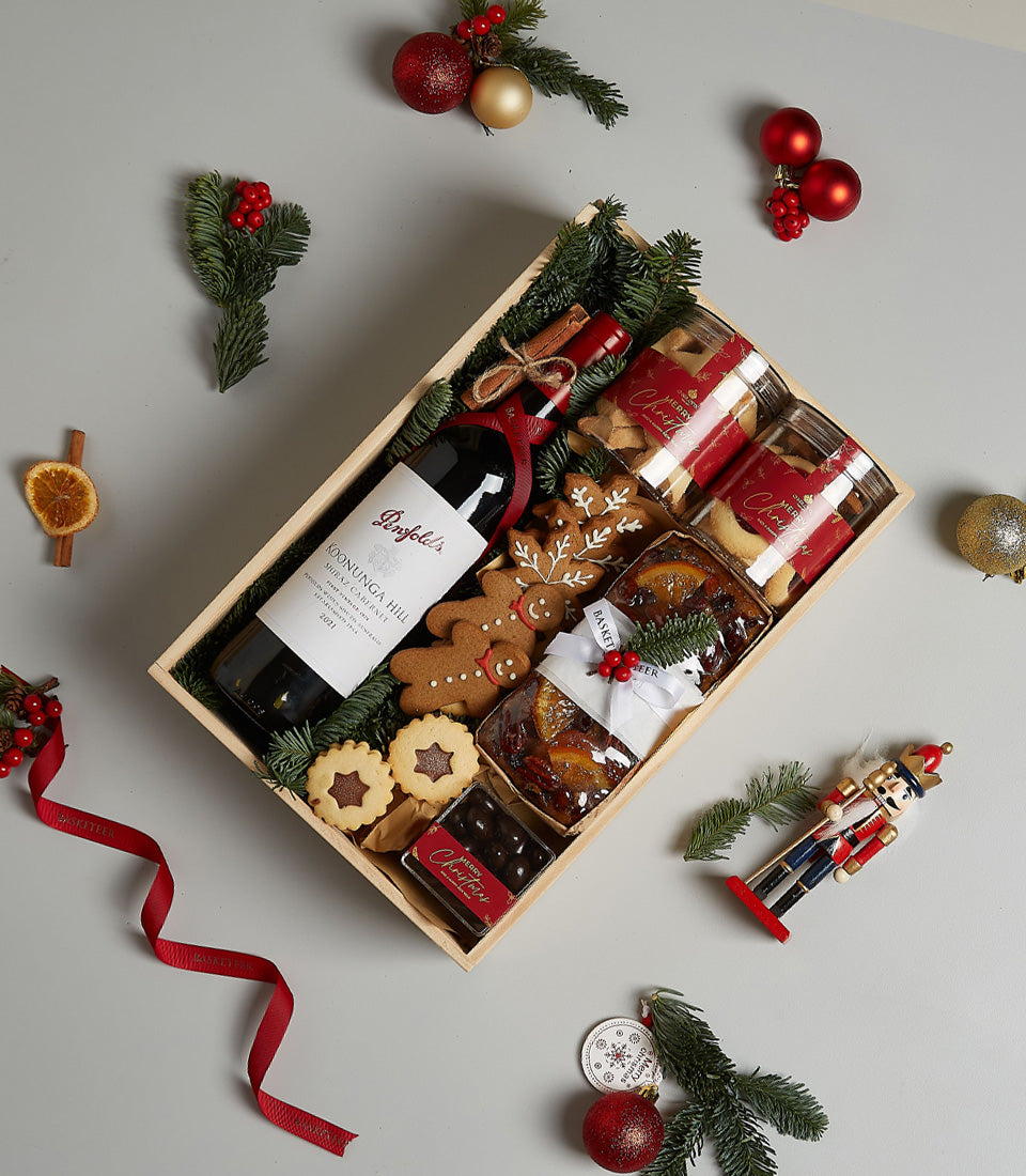 Festive Christmas hamper with Penfolds red wine, gingerbread cookies, shortbread, fruit cakes in wooden crate