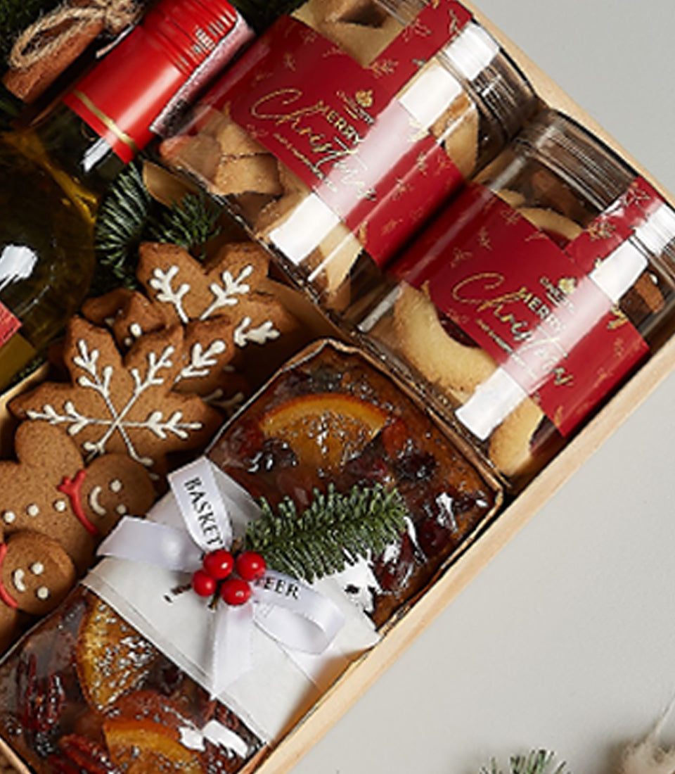 Festive white wine gift box with gingerbread cookies, Christmas treats, and fruitcake in wooden packaging