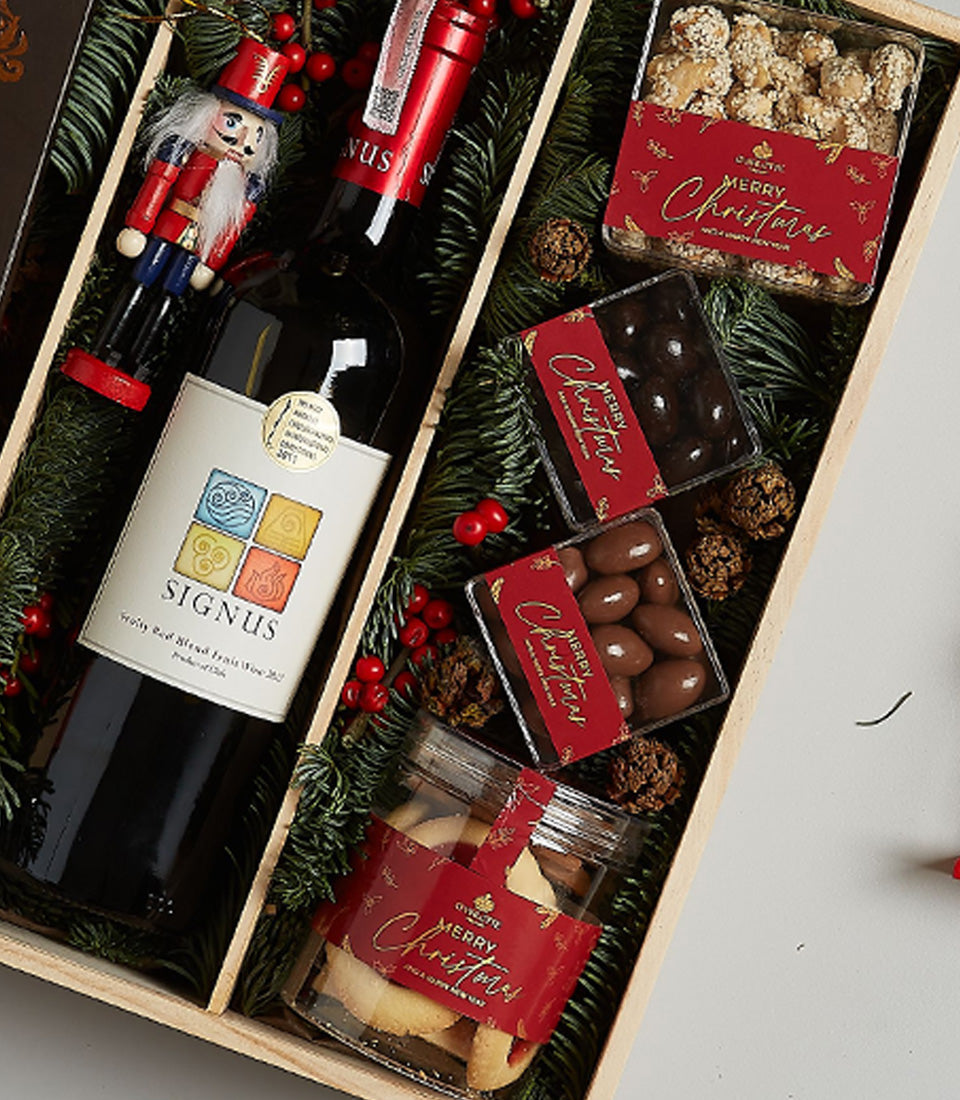 Premium red wine and gourmet chocolate treats Christmas gift box with festive evergreen décor