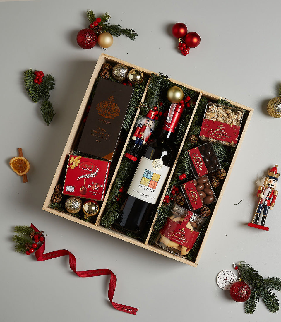 Premium holiday wine and gourmet treats gift box with red wine, chocolates, and festive decorations