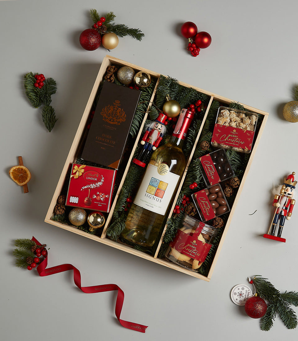 Premium white wine and gourmet treats Christmas hamper with chocolate, popcorn, and festive decorations