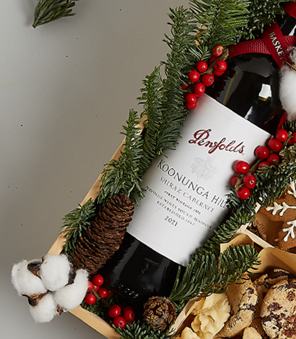 Festive red wine gift box with Penfolds Shiraz, gingerbread cookies, and holiday greenery