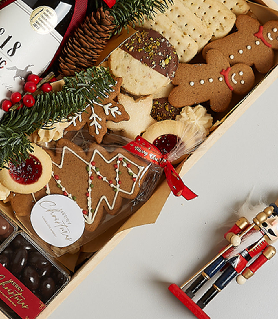 Red wine and artisan cookies Christmas gift box with gingerbread, shortbread, and chocolate treats