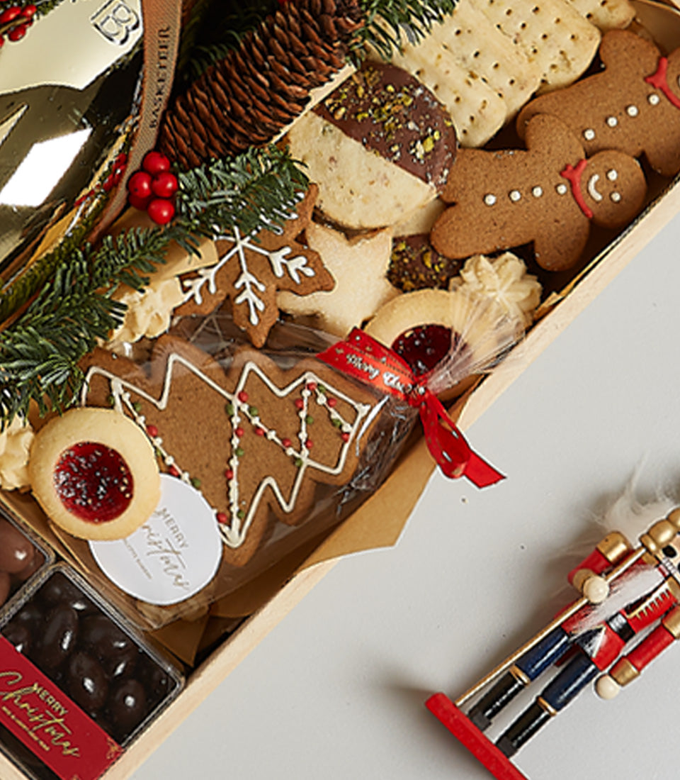 Golden gingerbread and shortbread Christmas gift box with champagne, festive cookies and chocolate treats