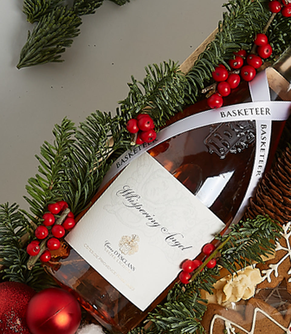 Rosé wine gift box with pine branches, red berries, gingerbread cookies, and Christmas baubles