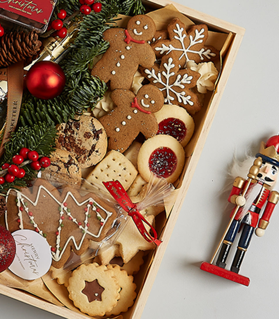 Wooden Christmas gift box with assorted festive cookies, prosecco, and holiday decorations