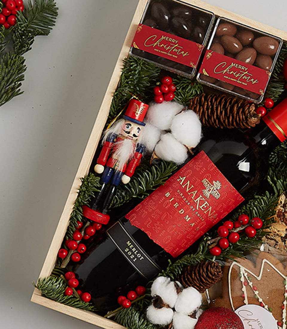 Premium red wine and chocolate Christmas gift hamper with festive greenery and gingerbread accents
