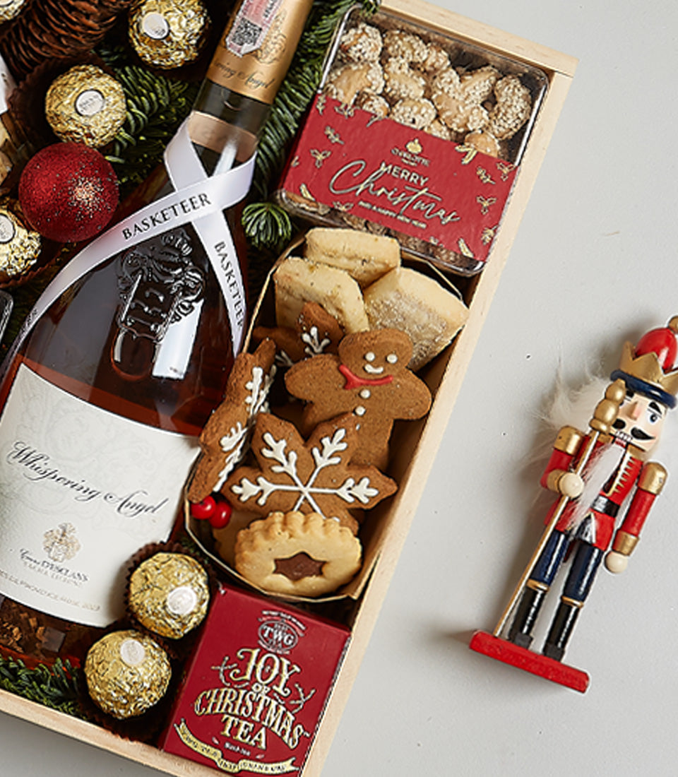 Rosé wine Christmas hamper with Ferrero Rocher chocolates, gingerbread cookies, and festive wooden nutcracker in light crate
