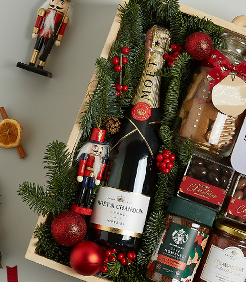Moët & Chandon champagne Christmas hamper with gingerbread, chocolate, coffee, and festive pine décor in wooden crate