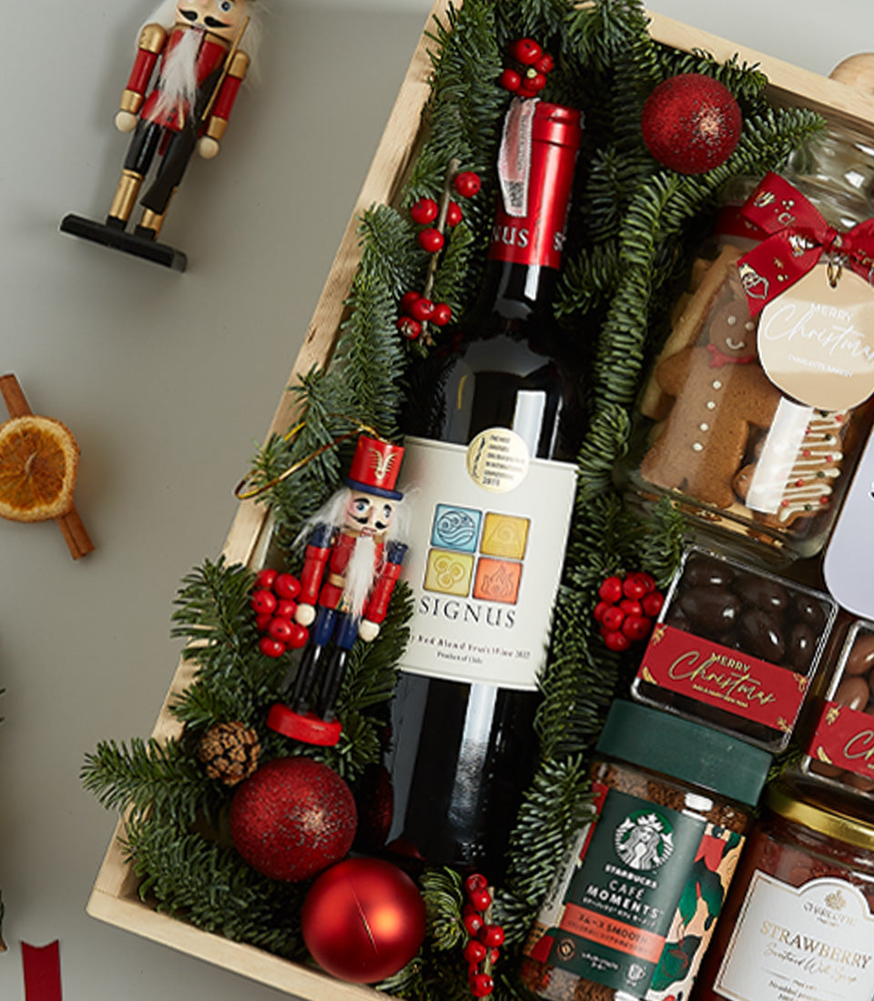 Premium red wine Christmas gift hamper with gourmet treats in wooden crate, pine garland, and festive nutcrackers