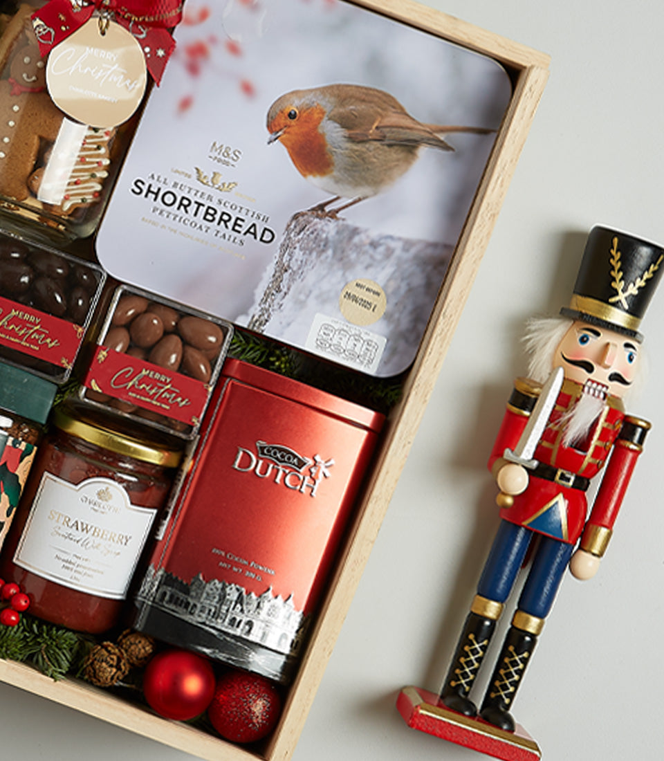 Luxury Christmas wine hamper with gourmet treats, hot chocolate, and festive decorations in wooden crate