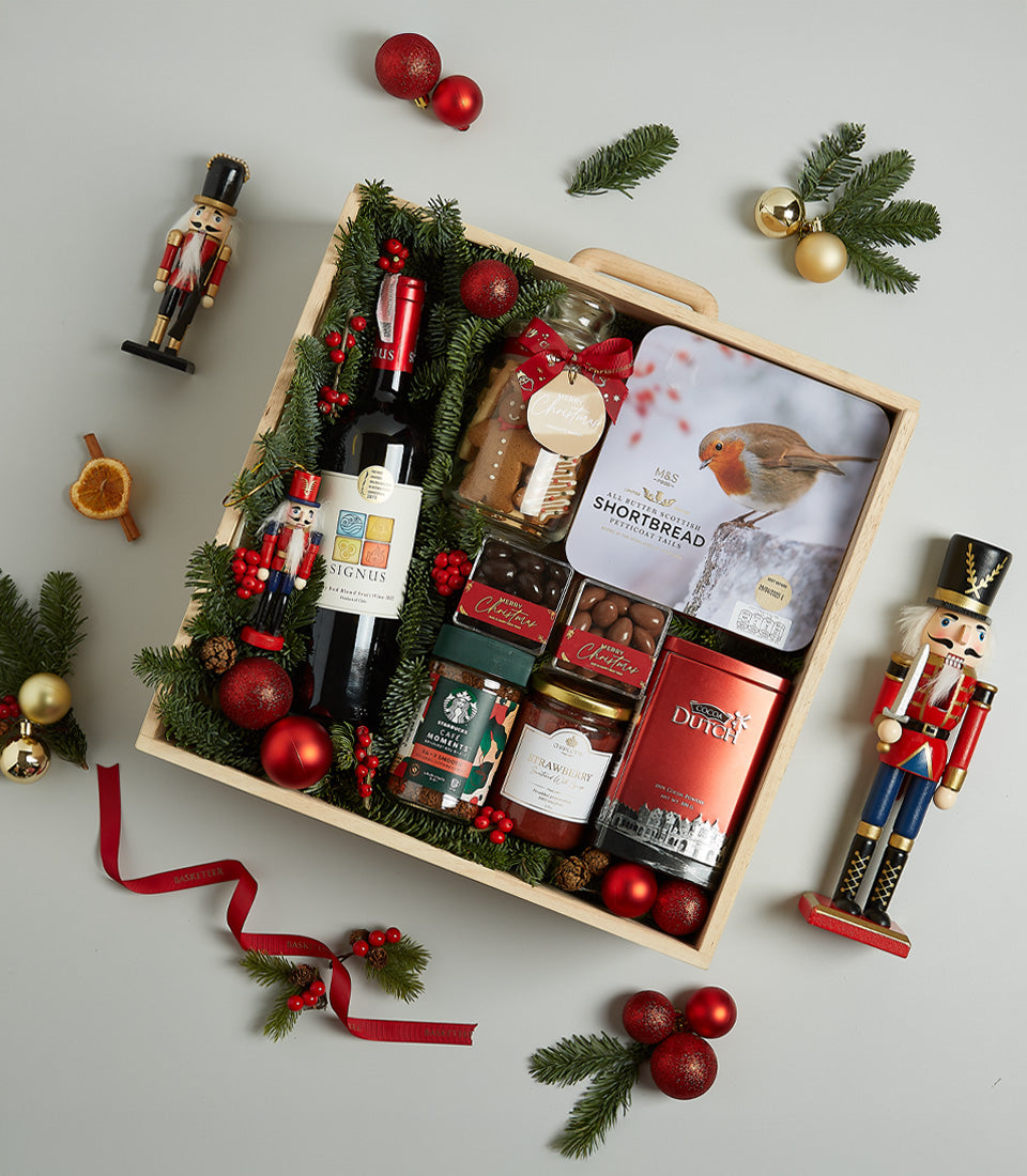 Luxury Christmas wine hamper with red wine, gourmet treats, and festive decorations in wooden crate
