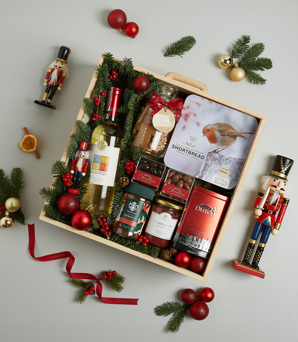 Festive gourmet hamper with white wine, shortbread, chocolates, and holiday treats in wooden crate