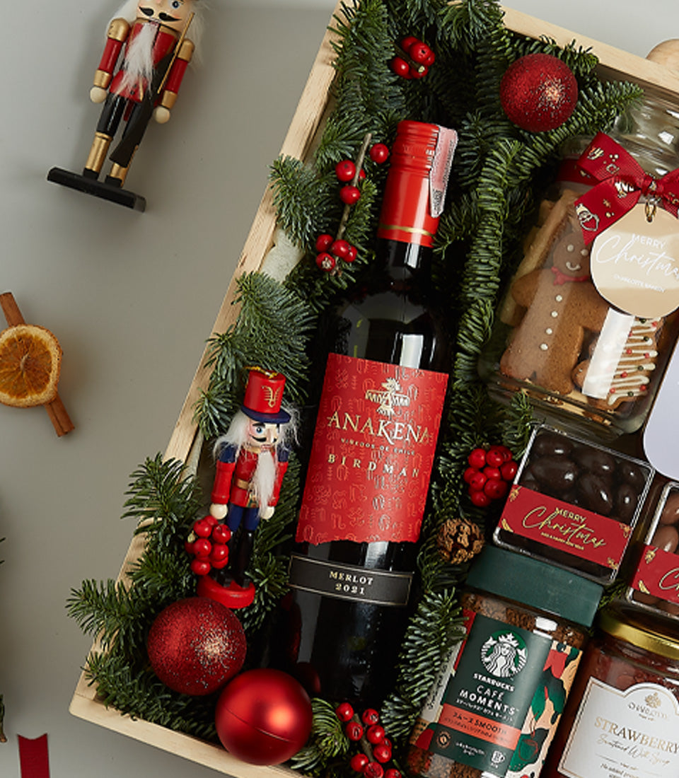 Premium red wine Christmas hamper with gourmet treats, festive nutcrackers, and holiday greenery in wooden tray