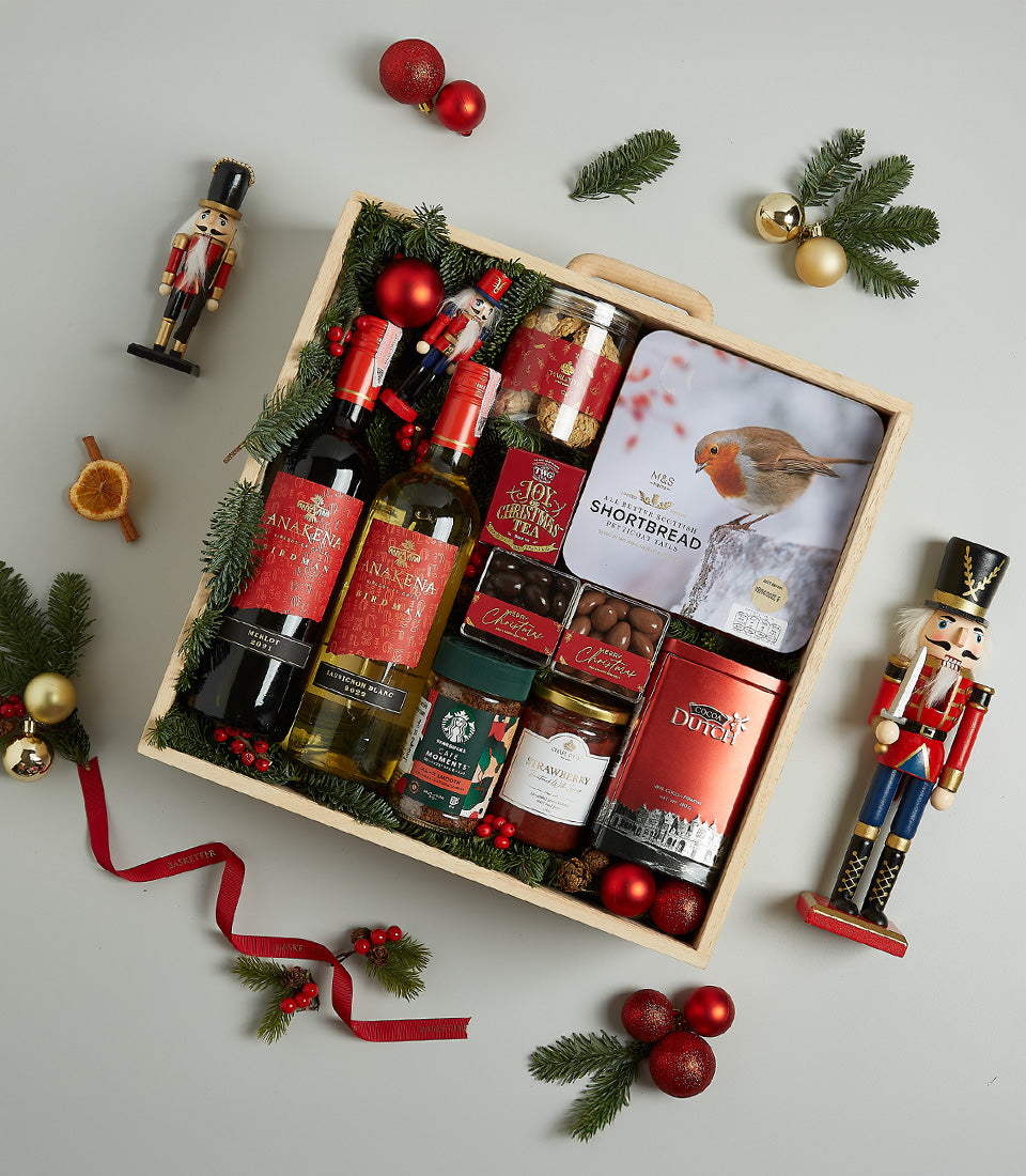 Festive Christmas wine hamper with red and white wines, gourmet chocolates, shortbread, and artisan treats in wooden crate