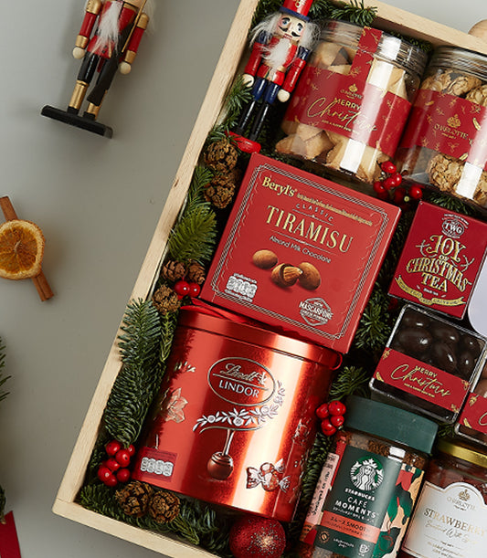 Premium Christmas gourmet hamper in wooden crate with chocolates, coffee, tea, and festive decorations