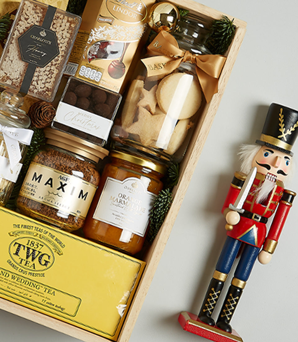 Golden tea and prosecco Christmas hamper with chocolates, coffee, and shortbread in wooden crate