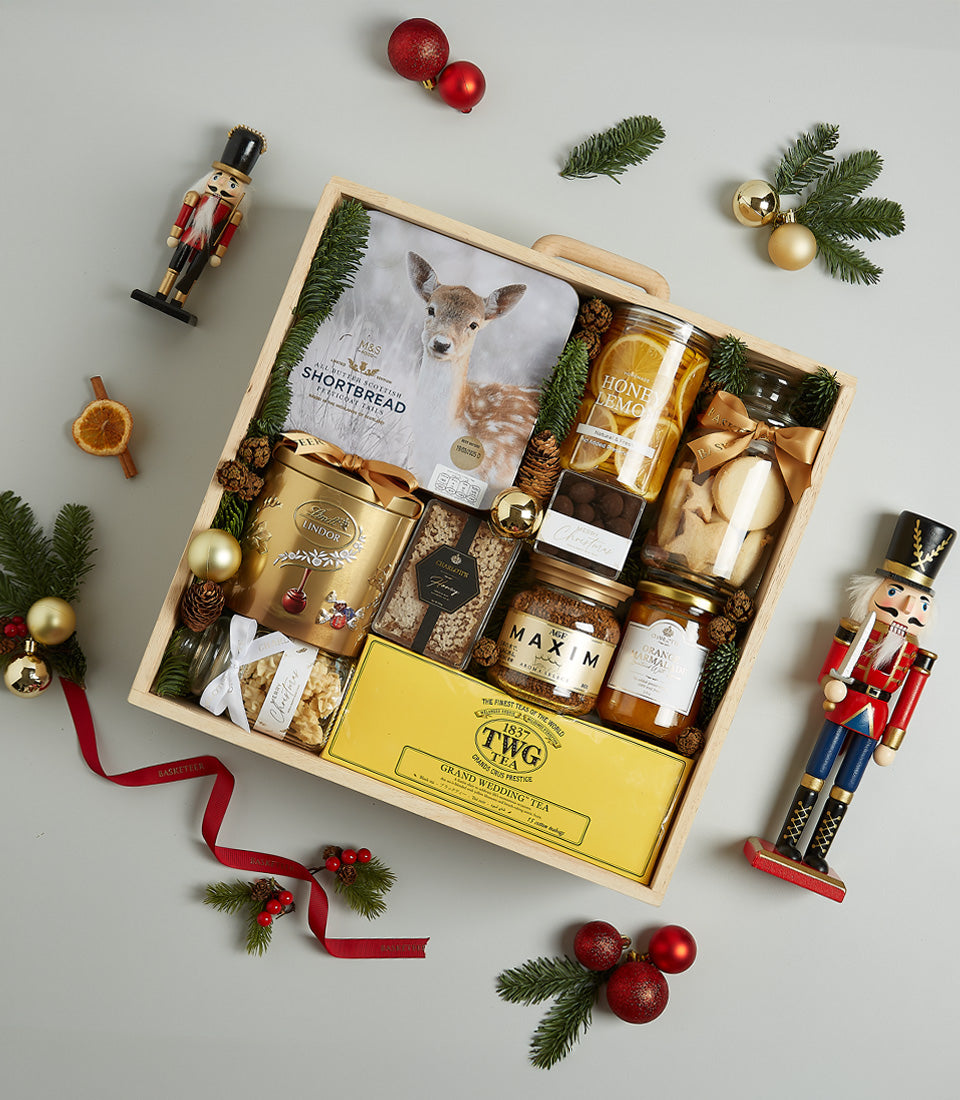 Golden gourmet Christmas hamper in wooden crate with shortbread, honey, chocolates, coffee, marmalade, tea, and festive