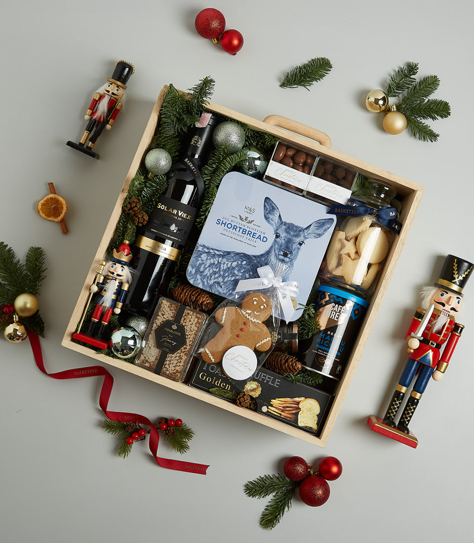 Festive wooden Christmas hamper with red wine, shortbread, gourmet treats, and holiday decorations