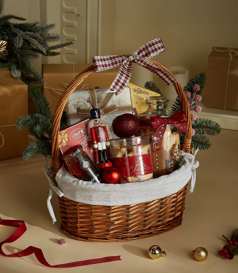 Basketeer holiday gift hamper: wicker basket filled with Lindt chocolates, cookies, and festive ornaments. Perfect premium hamper delivery in Thailand.
