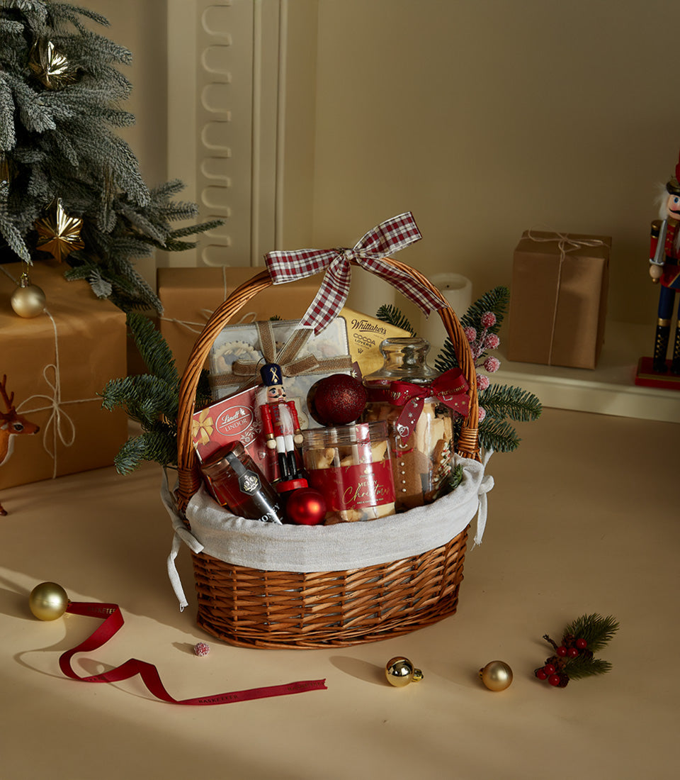 Basketeer holiday gift hamper in a wicker basket. Features gourmet cookies, chocolates, and a nutcracker. Premium corporate gift for Bangkok delivery.