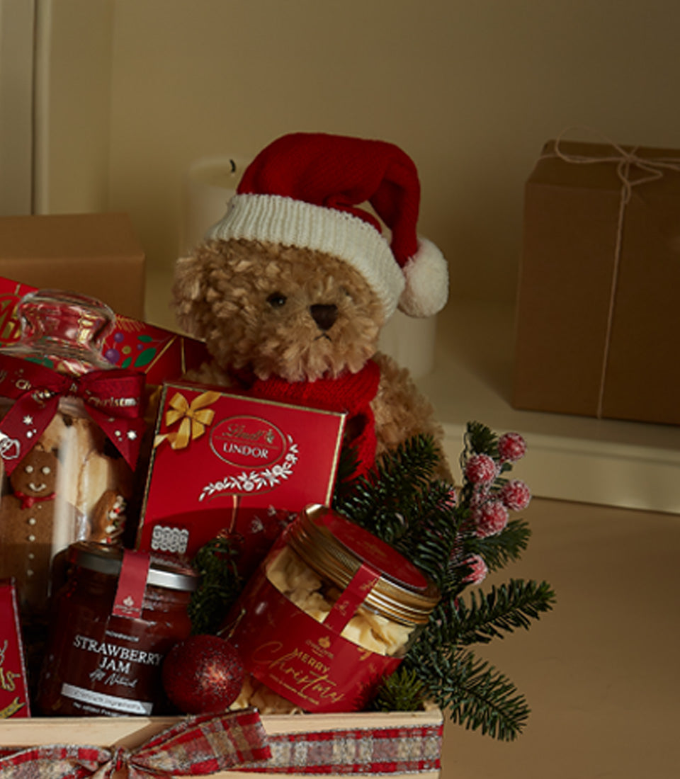 Festive Christmas gift hamper with teddy bear, gourmet chocolates, jams, and red plaid ribbon