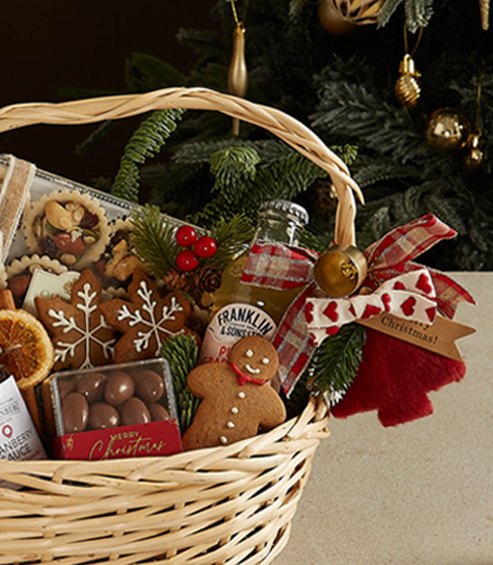 Festive Delights Christmas gift basket with gingerbread cookies, chocolate treats, and holiday wine in woven wicker