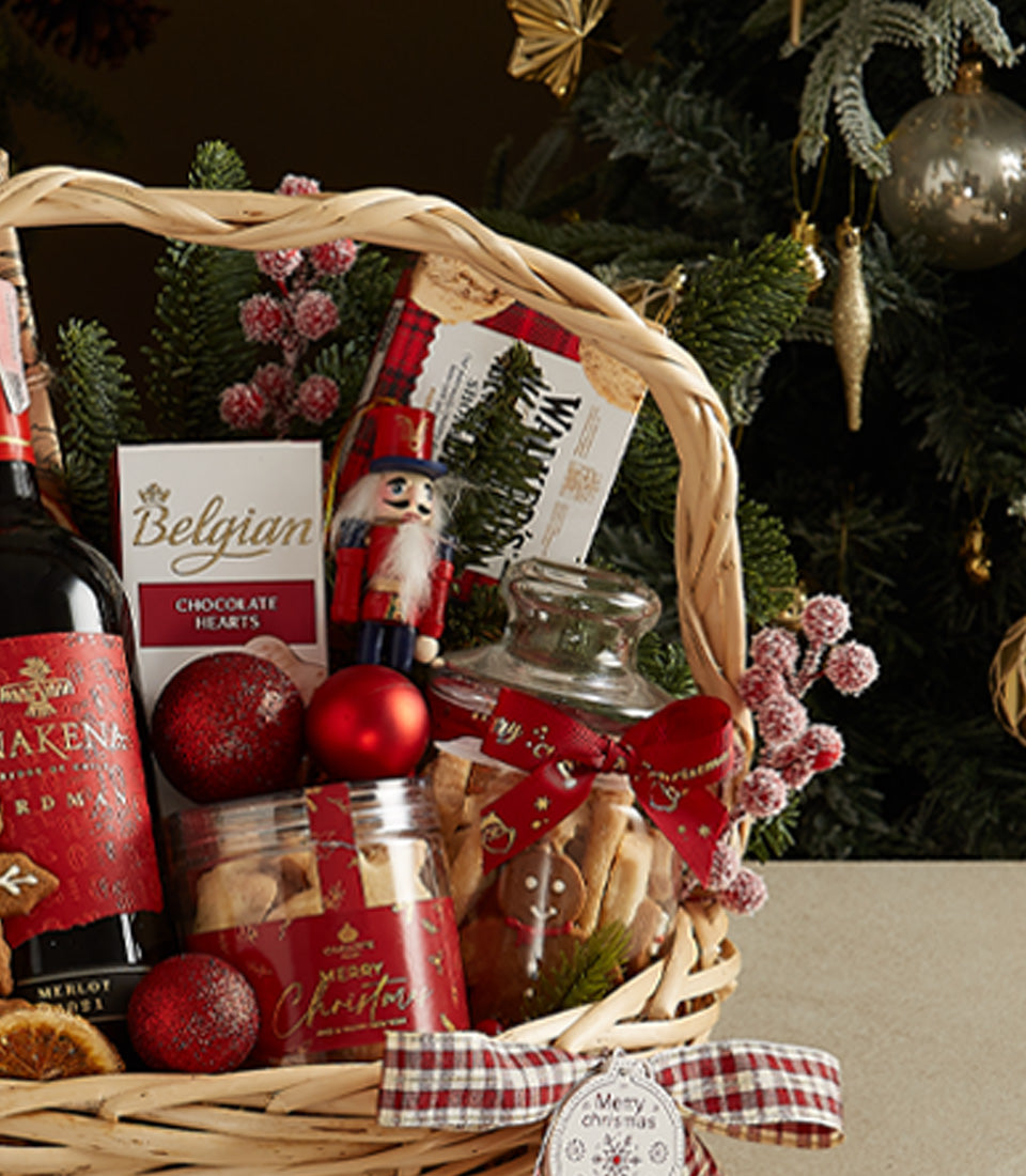 Woven luxury gift basket with red wine, Belgian chocolates, festive cookies, and Christmas baubles