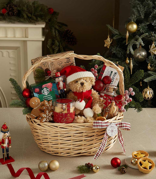 Festive Christmas gift basket with teddy bear, gourmet coffee, cookies, and holiday decorations in wicker