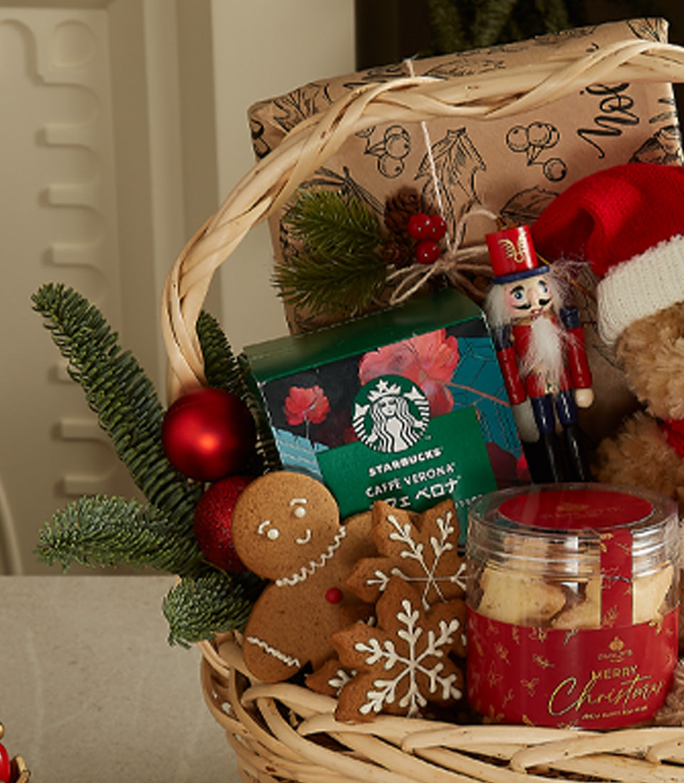 Festive Christmas gift basket with teddy bear, gingerbread cookies, coffee, and holiday decorations in woven basket