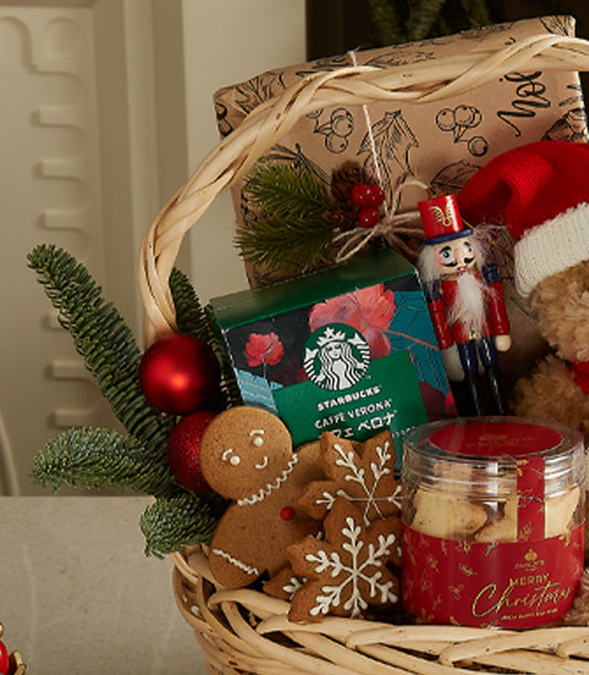 Festive Christmas gift basket with teddy bear, gingerbread cookies, coffee, and holiday decorations in woven basket