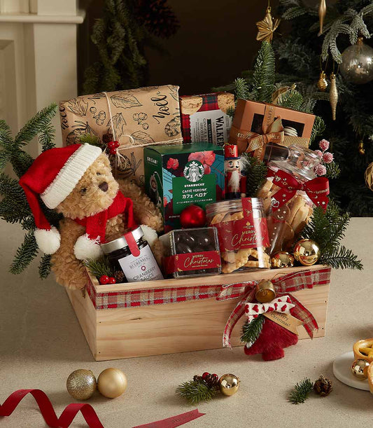 Festive wooden Christmas gift crate with plaid ribbon, Santa teddy bear, gourmet treats, and holiday decorations