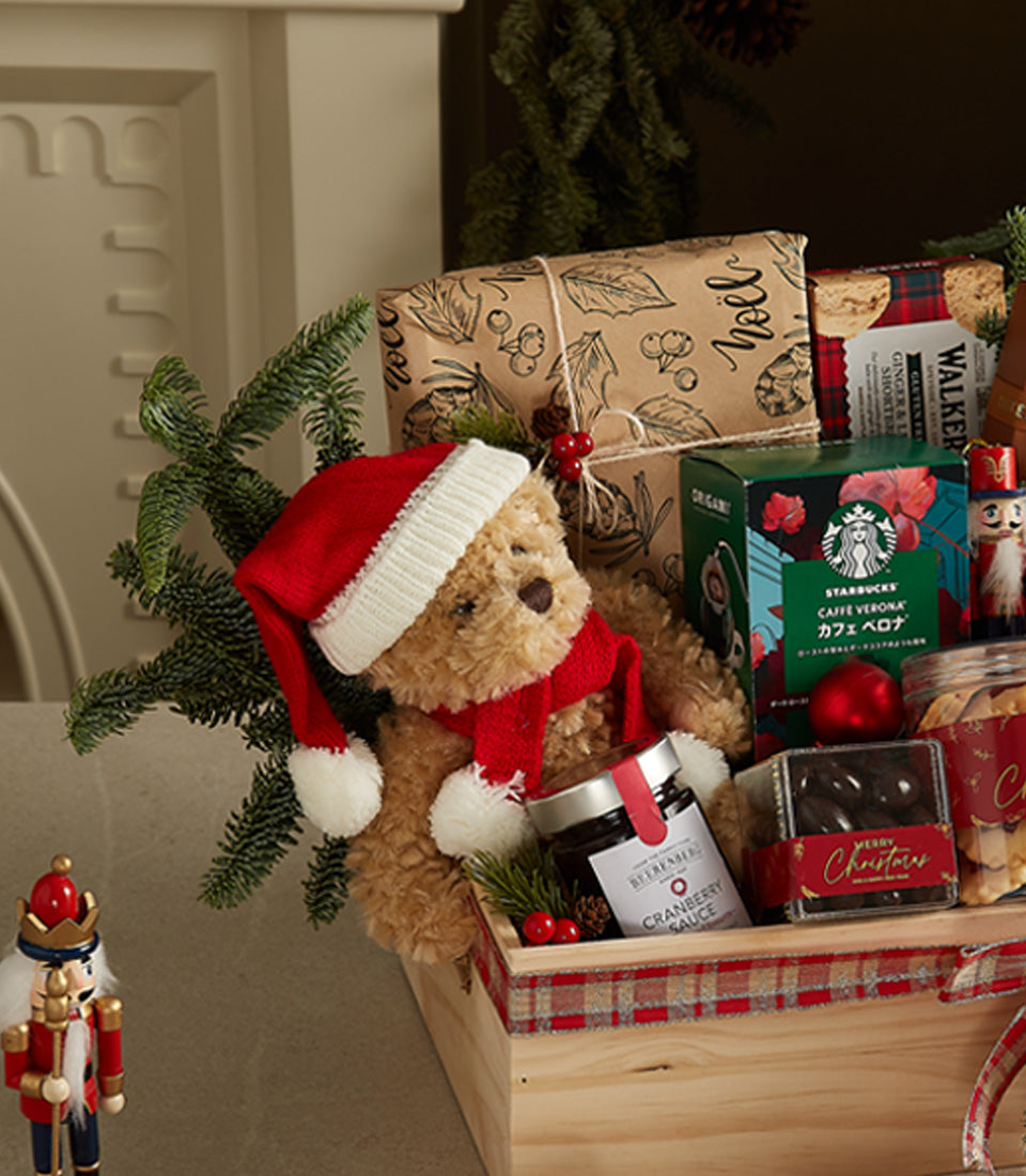 Wooden holiday gift crate with Santa teddy bear, gourmet treats, and festive décor in red plaid ribbon