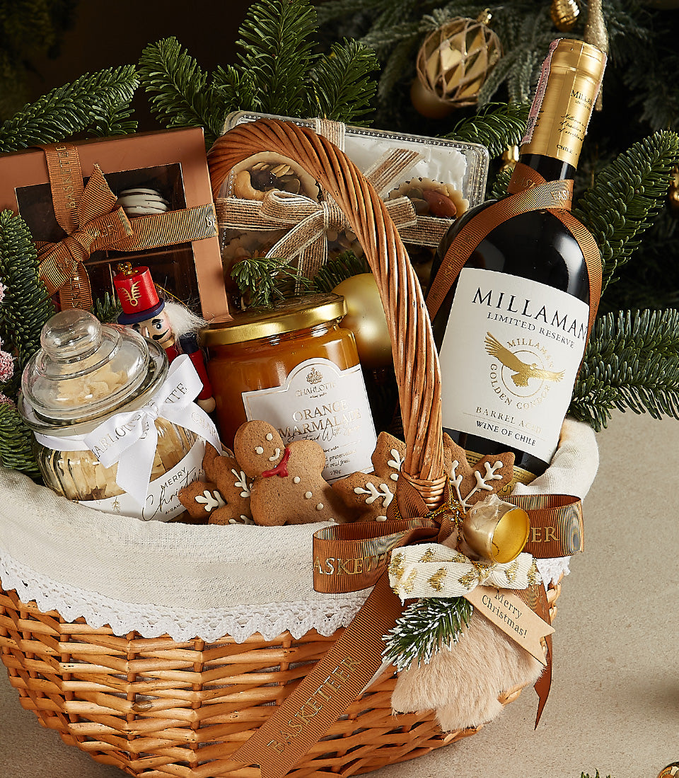 Woven wicker Christmas hamper with red wine, gourmet treats, and festive decorations
