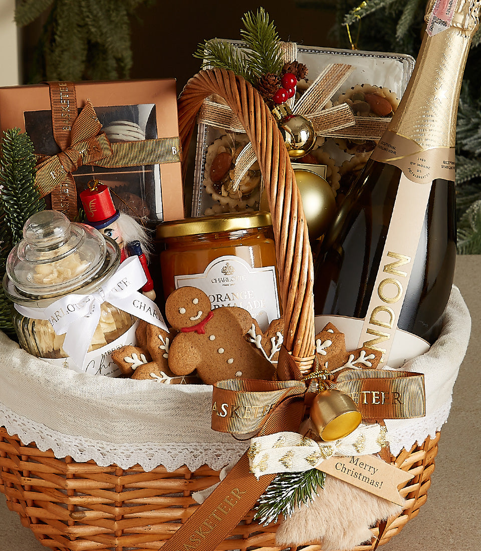 Woven wicker Christmas gift basket with champagne, marmalade, cookies, chocolates, and festive gold ornaments
