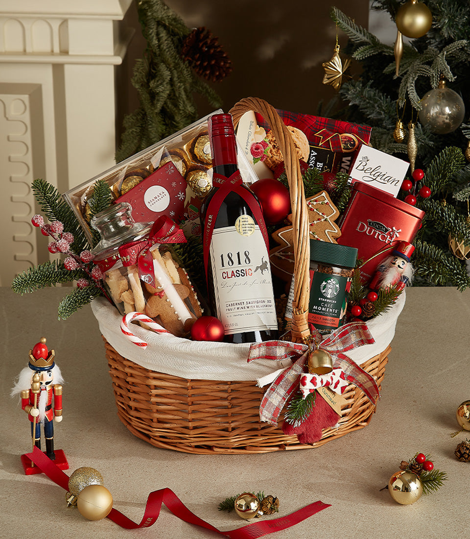 Festive wicker basket with red wine, gourmet chocolates, cookies, and coffee, tied with plaid ribbon for Christmas gifting