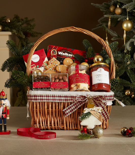 Festive Christmas gift basket with shortbread, chocolates, gingerbread, and jam in wicker with plaid liner