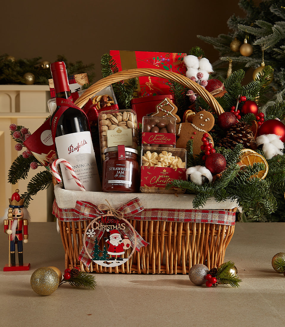 Woven wicker Christmas wine basket with red wine, gourmet treats, and festive holiday decorations