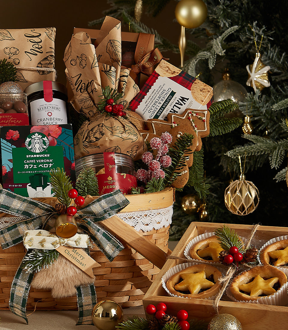 Festive wicker Christmas hamper with prosecco, gourmet treats, and plaid ribbon beside star pastries with berries
