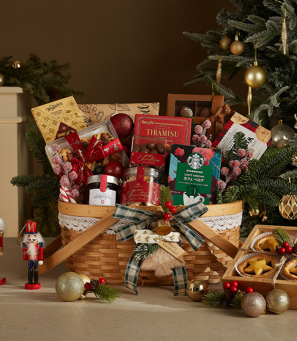Woven Christmas gift basket with gourmet chocolates, coffee, jam, and festive treats tied with plaid bow and golden bell