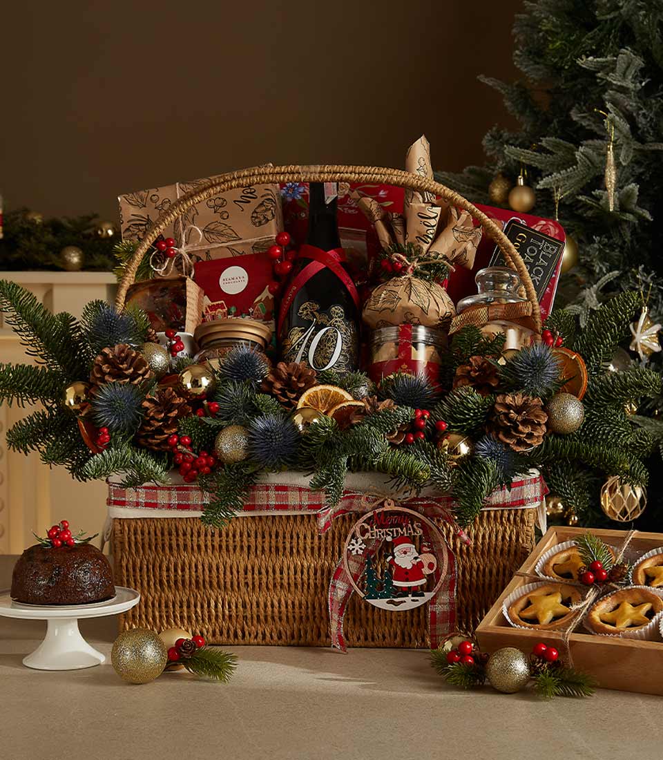 Luxury Christmas wine hamper with red wines, gourmet treats, fresh evergreens, and festive decorations in wicker basket