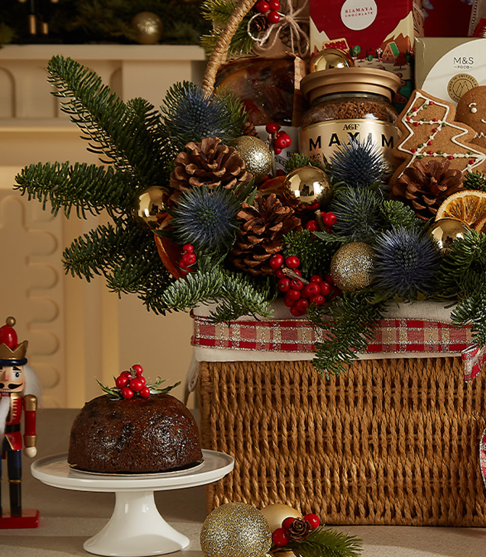 Deluxe Christmas hamper with wicker basket, festive greenery, gourmet treats and red plaid ribbon