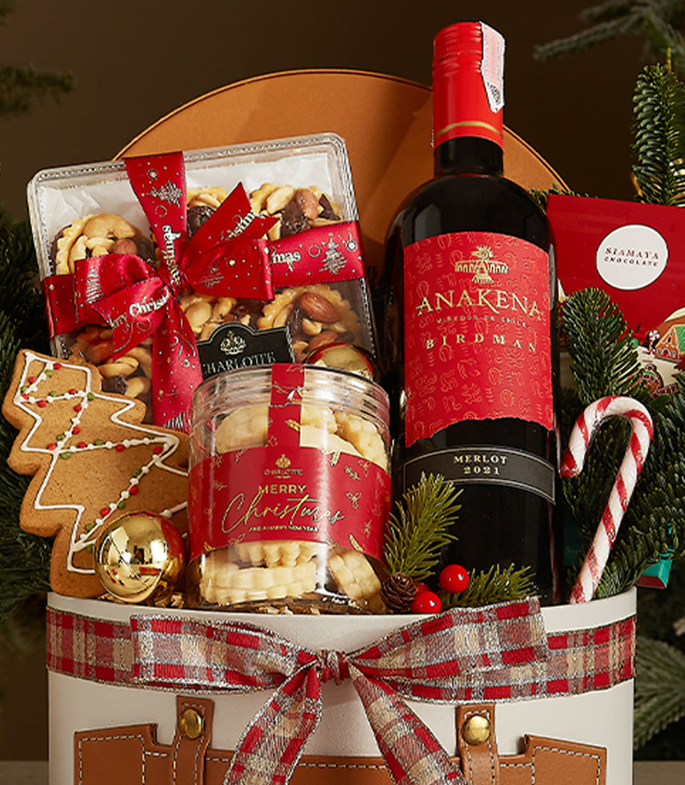 Luxury Christmas wine gift basket with Merlot, gourmet nuts, artisan cookies, and festive ornaments in premium packaging
