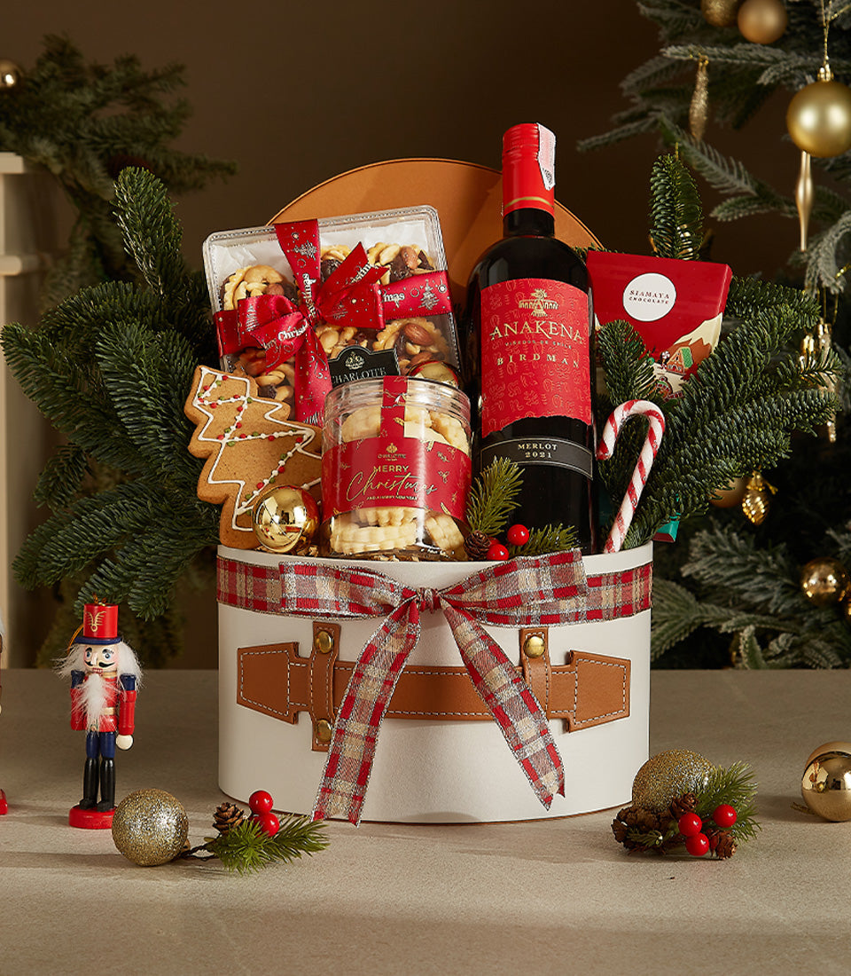 Elegant white leather Christmas wine gift hamper with Merlot, nuts, cookies, and festive red plaid ribbon